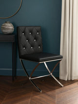 Black leather dining chair with diamond tufted back and chrome legs on wood floor