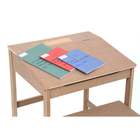 Natural wood desk with a slanted top, featuring three colorful notebooks in red, green, and blue placed on the surface. The desk has a lower shelf for additional storage. A matching stool is positioned nearby, complementing the desk's design