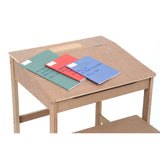 Natural wood desk with a slanted top, featuring three colorful notebooks in red, green, and blue placed on the surface. The desk has a lower shelf for additional storage. A matching stool is positioned nearby, complementing the desk's design