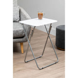 A folding table with a white top and silver metal legs, positioned next to a gray sofa and a dark round side table, with a small plant in a brown pot placed on the table's surface. The floor is light wood