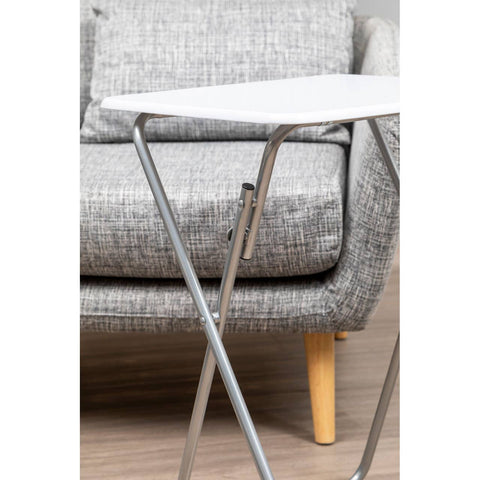 Folding table with a white top and silver metal legs positioned next to a gray upholstered sofa with wooden legs. The table is compact and designed for easy storage, complementing the modern living room setting