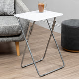 Folding table with a sleek white top and silver metal legs, positioned next to a gray upholstered sofa and a round gray ottoman on a wooden floor, with a small potted plant on the table's surface