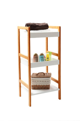 Versi White High Gloss 3 Tier Small Shelf Unit featuring a sleek white high gloss finish with three open shelves, supported by a natural wood frame. The top shelf displays a folded dark brown blanket, while the middle shelf holds a pair of shoes and a colorful decorative item. The bottom shelf contains a woven basket, adding a touch of texture to the overall design