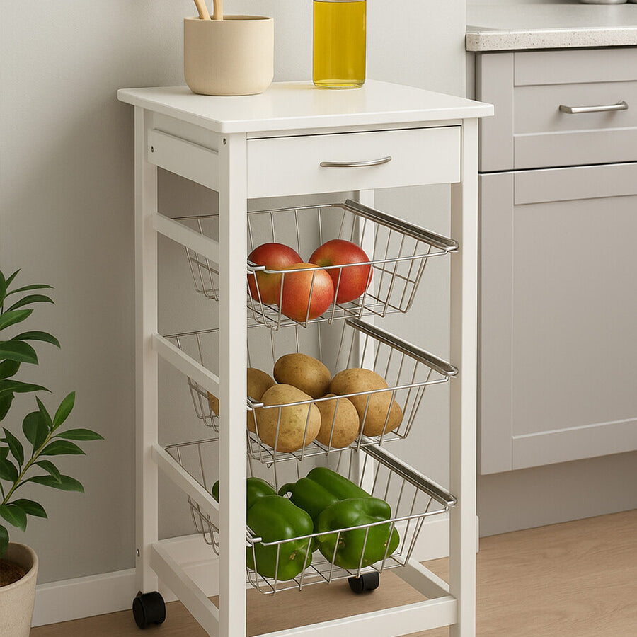 White veneer finish kitchen trolley with a flat top, featuring a bottle of olive oil and wooden utensils. The trolley has three open shelves displaying apples, pears, and limes, and is mounted on wheels for easy mobility. The background includes a light-colored kitchen setting with cabinets