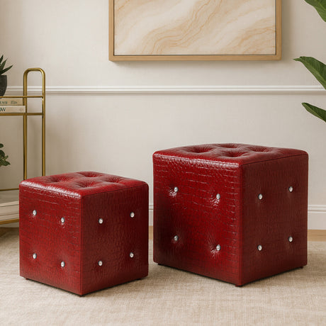 Two red stools with a crocodile leather effect, one larger and one smaller, featuring tufted tops and decorative silver studs. They are placed on a light-colored floor against a neutral wall, with a piece of abstract art visible in the background
