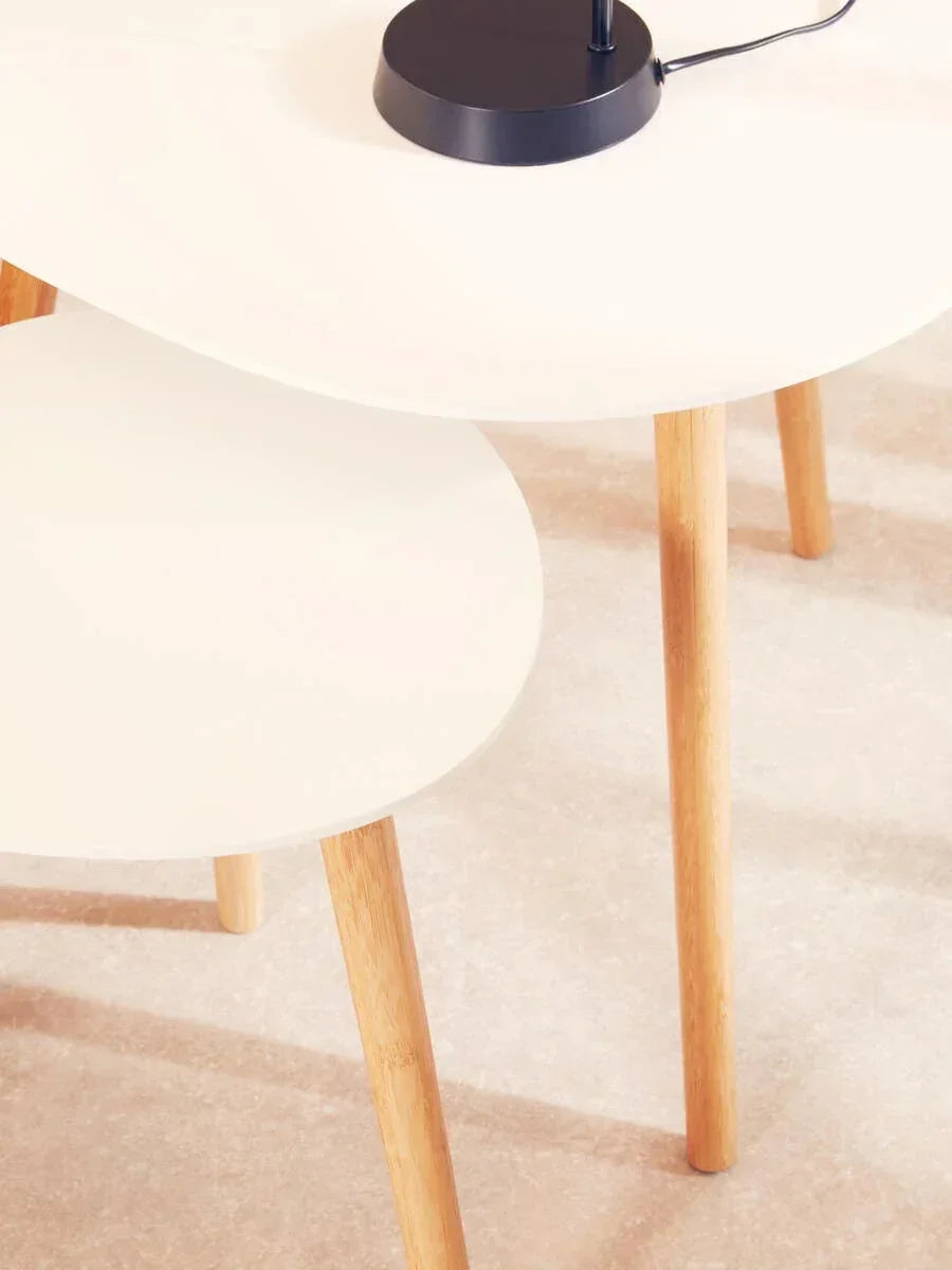 Modern nesting coffee tables with white tops and light wooden legs on beige flooring
