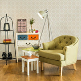 A black three-tier shelf unit stands against a light-colored wall, showcasing various decorative items. Next to it, a green upholstered armchair with button detailing is positioned beside a small white side table. The side table holds a potted plant and a decorative bowl. A floor lamp with a white shade illuminates the space, while a colorful storage unit with orange and blue drawers adds a pop of color to