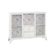 White cabinet featuring two doors and two drawers, with a floral pattern on the glass panels of the doors. The cabinet has a sleek design and stands on four legs, providing a modern touch to home decor