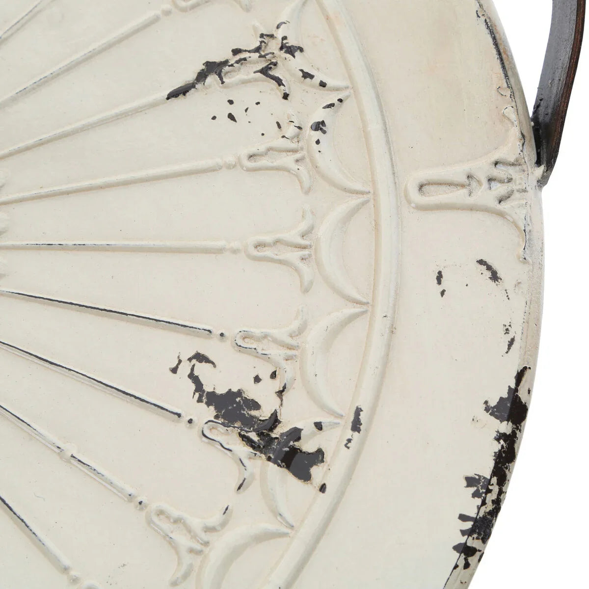 Close-up of distressed cream metal table with decorative embossed pattern and aged detail