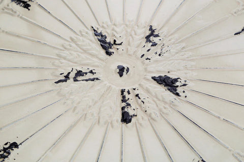Close view of cream ceramic table top with embossed floral pattern and distressed finish