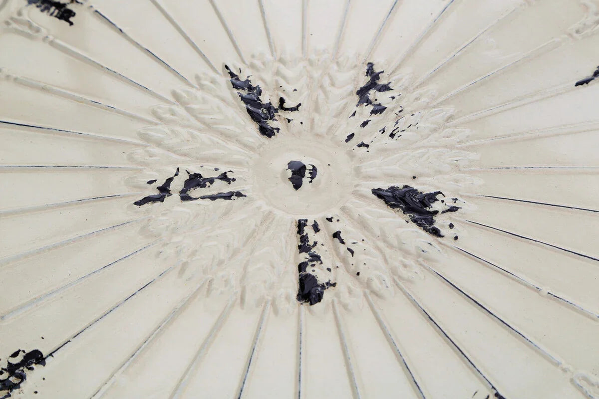 Close view of cream ceramic table top with embossed floral pattern and distressed finish