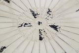 Close view of cream ceramic table top with embossed floral pattern and distressed finish