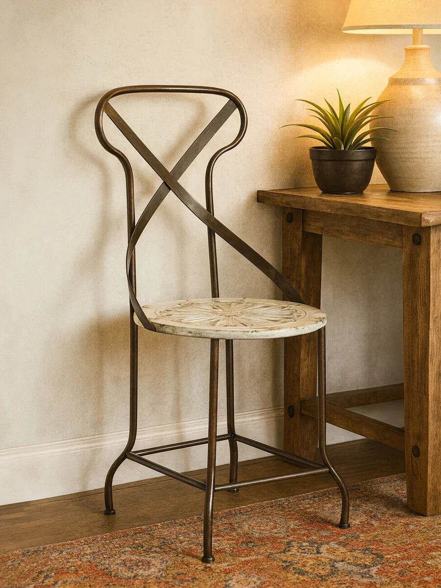 Metal accent chair with cross back and round patterned seat beside a wooden side table