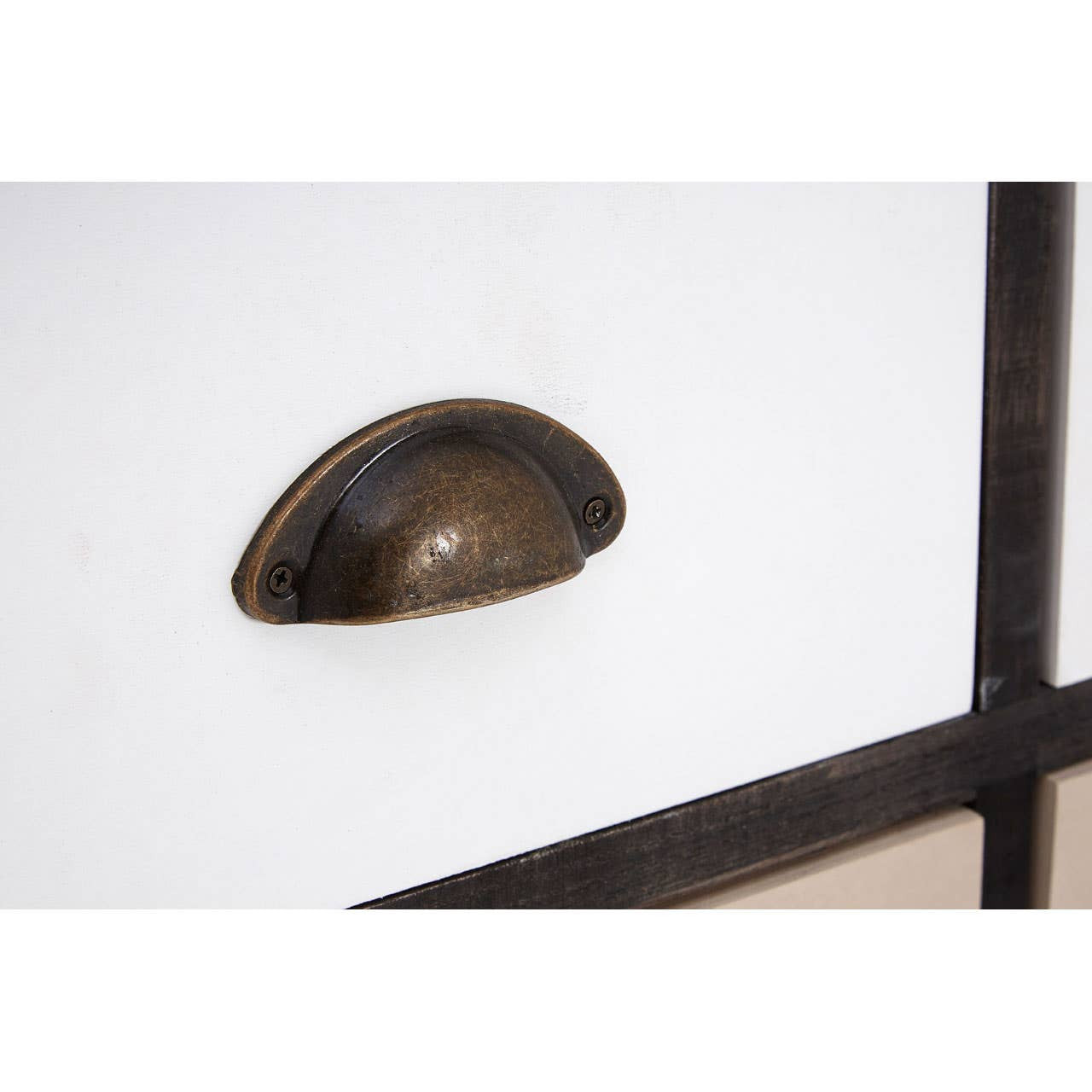 Close-up view of a bronze drawer pull on a white drawer front, showcasing a sleek and modern design. The surrounding area features a black frame, highlighting the contrast between the white and dark elements