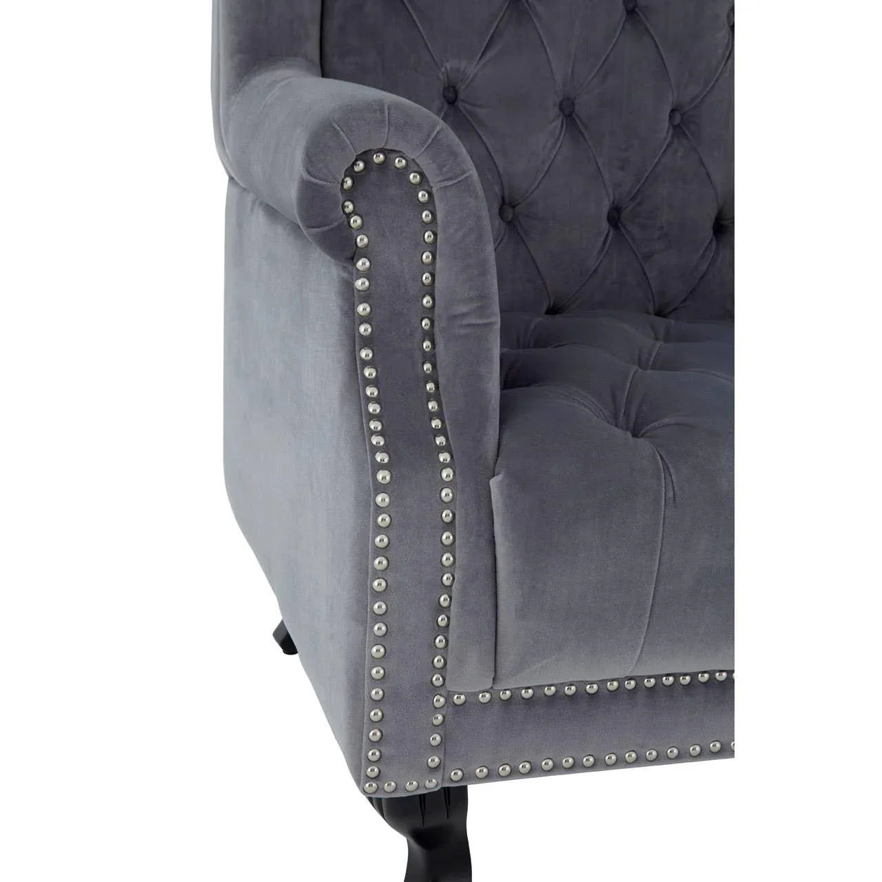 Grey velvet armchair with button tufting and silver stud detailing on arm and base