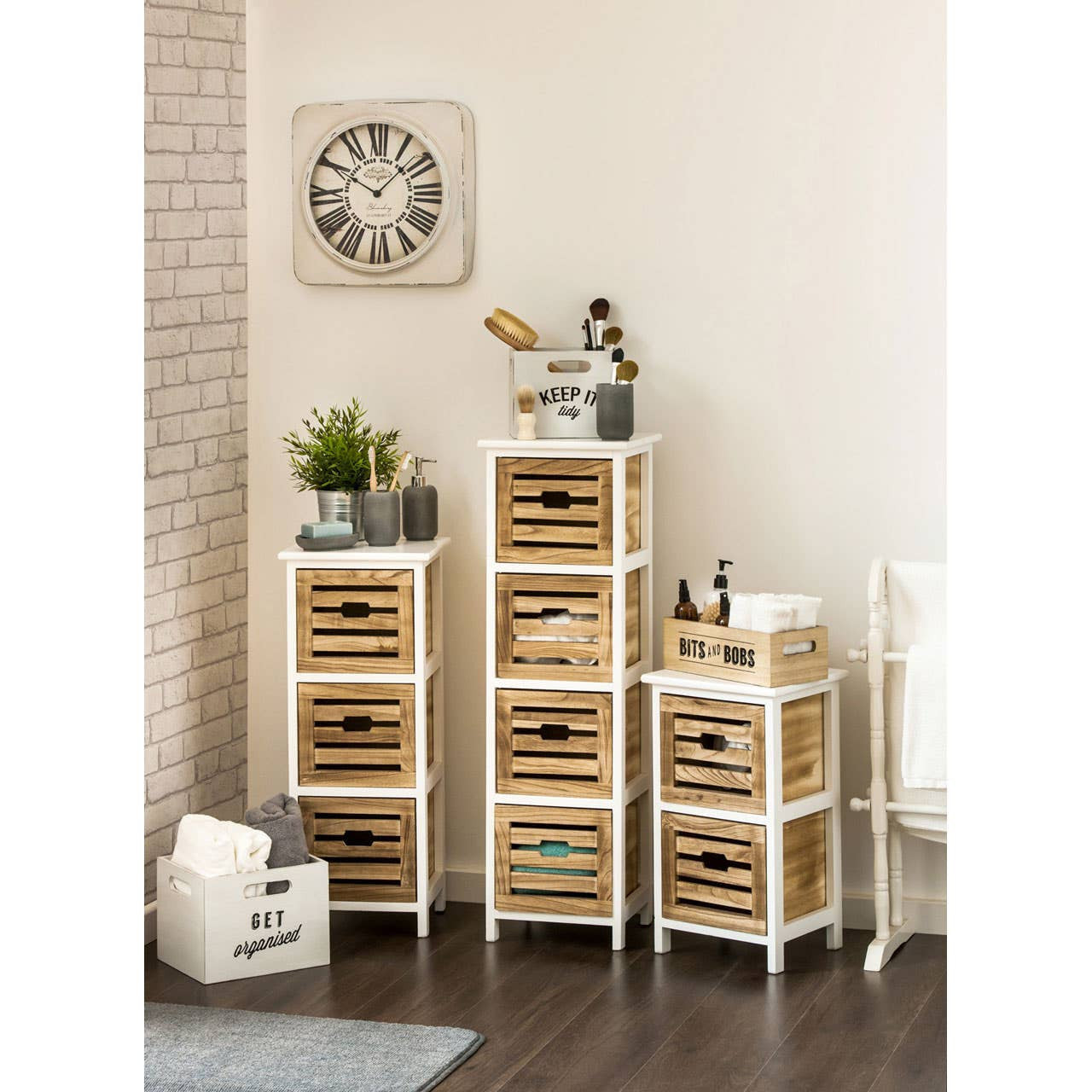 Portsmouth 3 Drawer Chest featuring a white wooden frame with three woven baskets as drawers, set against a light-colored wall. The chest is styled with decorative items, including a plant and a clock, on top, with a cozy, modern aesthetic