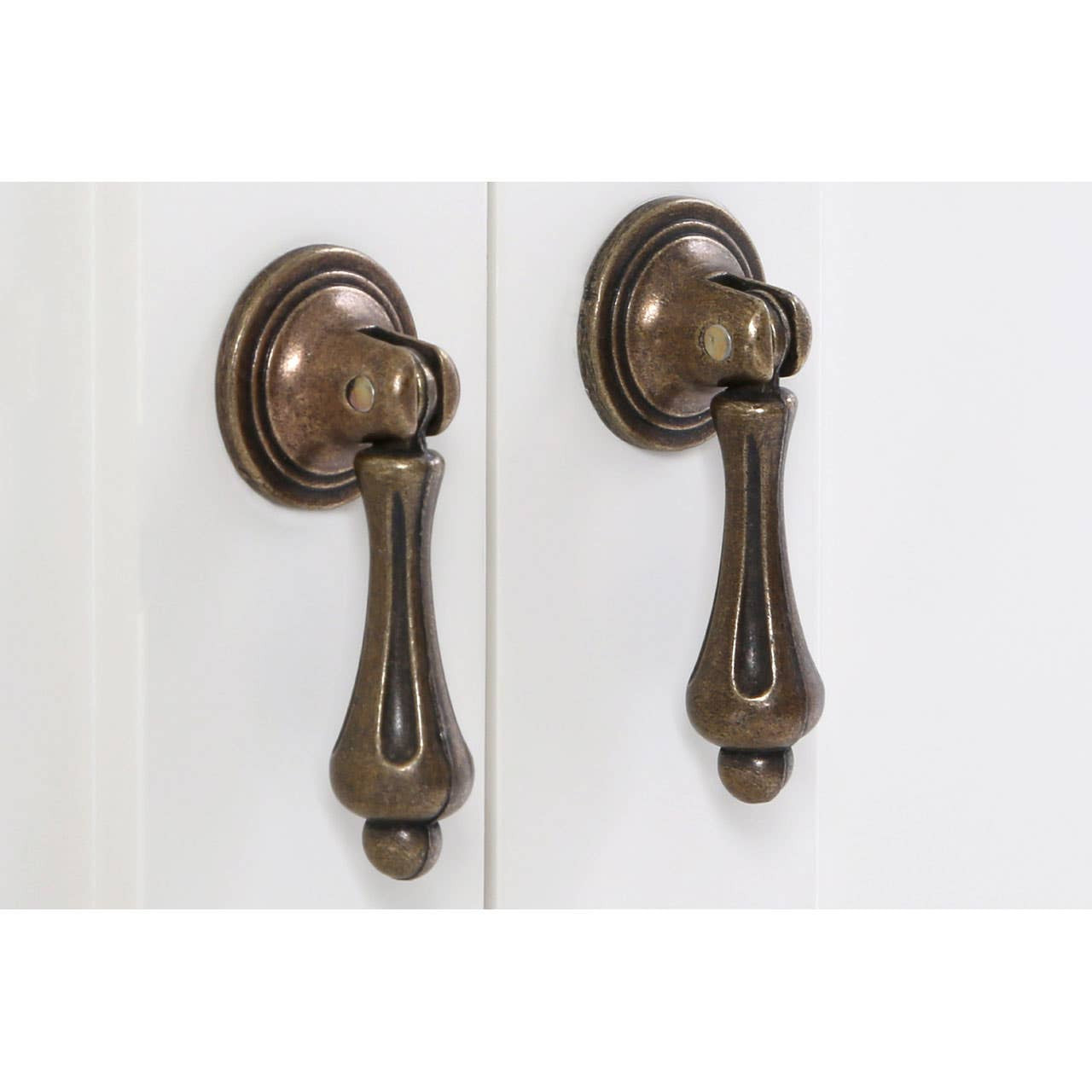Close-up view of two decorative bronze cabinet handles on a double door cabinet with an ivory finish. The handles feature a classic design, adding an elegant touch to the furniture piece