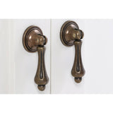 Close-up view of two decorative bronze cabinet handles on a double door cabinet with an ivory finish. The handles feature a classic design, adding an elegant touch to the furniture piece