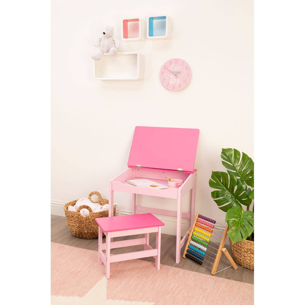 Three white floating wall cubes arranged in a staggered formation on a light-colored wall. The cubes are empty, showcasing their open design. A pink chair and a small pink stool are positioned nearby on a soft rug, with a colorful stack of books and a potted plant visible in the corner. Decorative wall art and a clock are also displayed above the cubes