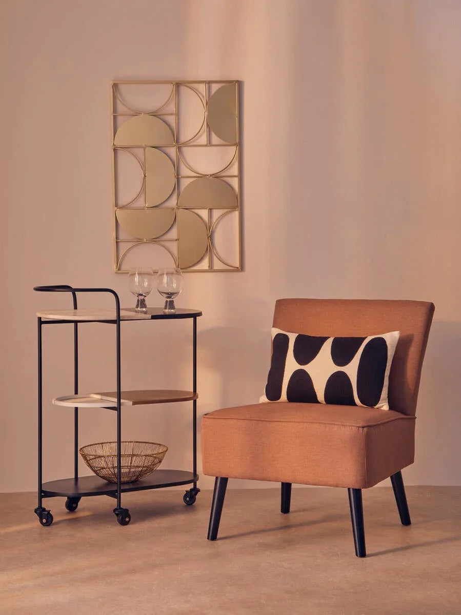 Modern accent chair with black legs and patterned cushion beside metal bar cart on wheels