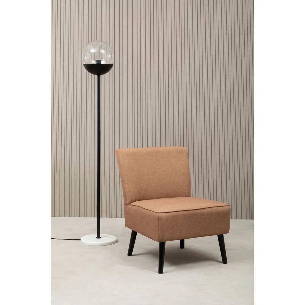 Brown upholstered accent chair with black legs beside modern floor lamp in minimalist room