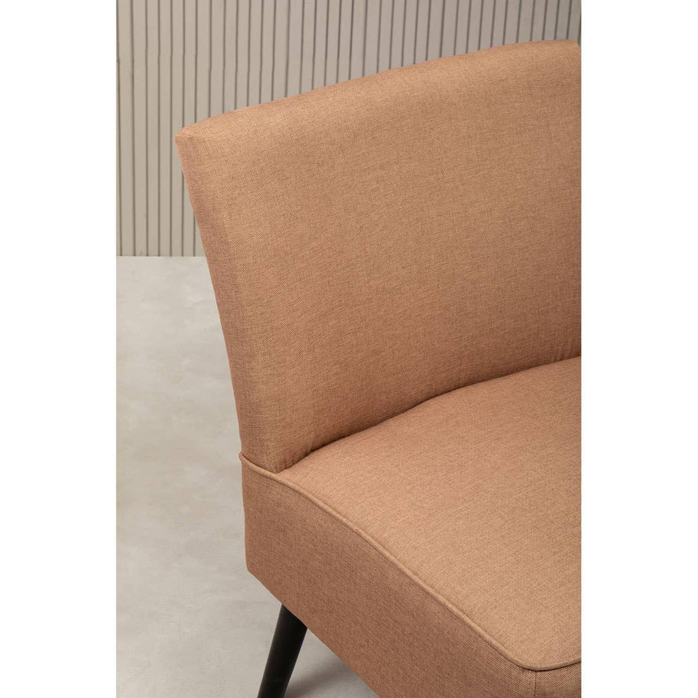 Closeup of tan fabric accent chair with black legs against a neutral background