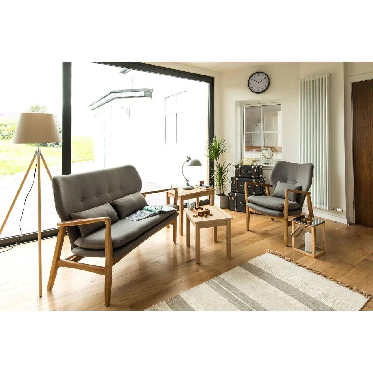 Grey fabric sofa set with wooden frames in modern living room with large window and coffee tables