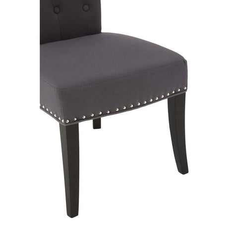 Dark grey upholstered dining chair with silver stud detailing and black wooden legs