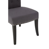 Dark grey upholstered dining chair with silver stud detailing and black wooden legs