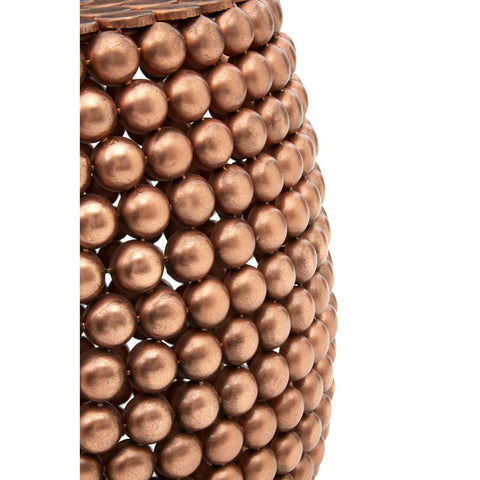 A close-up view of a barrel stool featuring a copper finish, showcasing a textured surface with a pattern of raised circular elements. The stool has a rounded shape and a warm metallic sheen