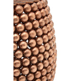A close-up view of a barrel stool featuring a copper finish, showcasing a textured surface with a pattern of raised circular elements. The stool has a rounded shape and a warm metallic sheen