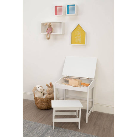 A white children's desk with a matching stool, positioned against a light-colored wall. The desk features a slanted top and is accompanied by a small basket filled with toys or art supplies. Above the desk, there are colorful wall-mounted storage boxes in red, blue, and yellow, adding a playful touch to the setup. The floor is a neutral tone, complementing the overall bright and cheerful aesthetic