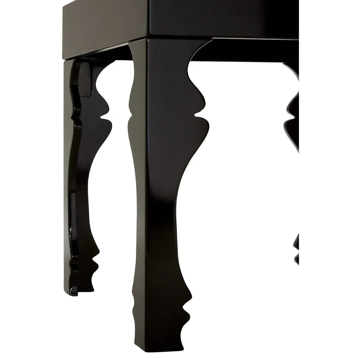 Glossy black wooden table legs with carved detailing, close-up corner view