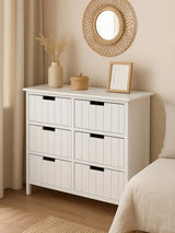 White wooden chest of drawers with six drawers in a neutral bedroom setting