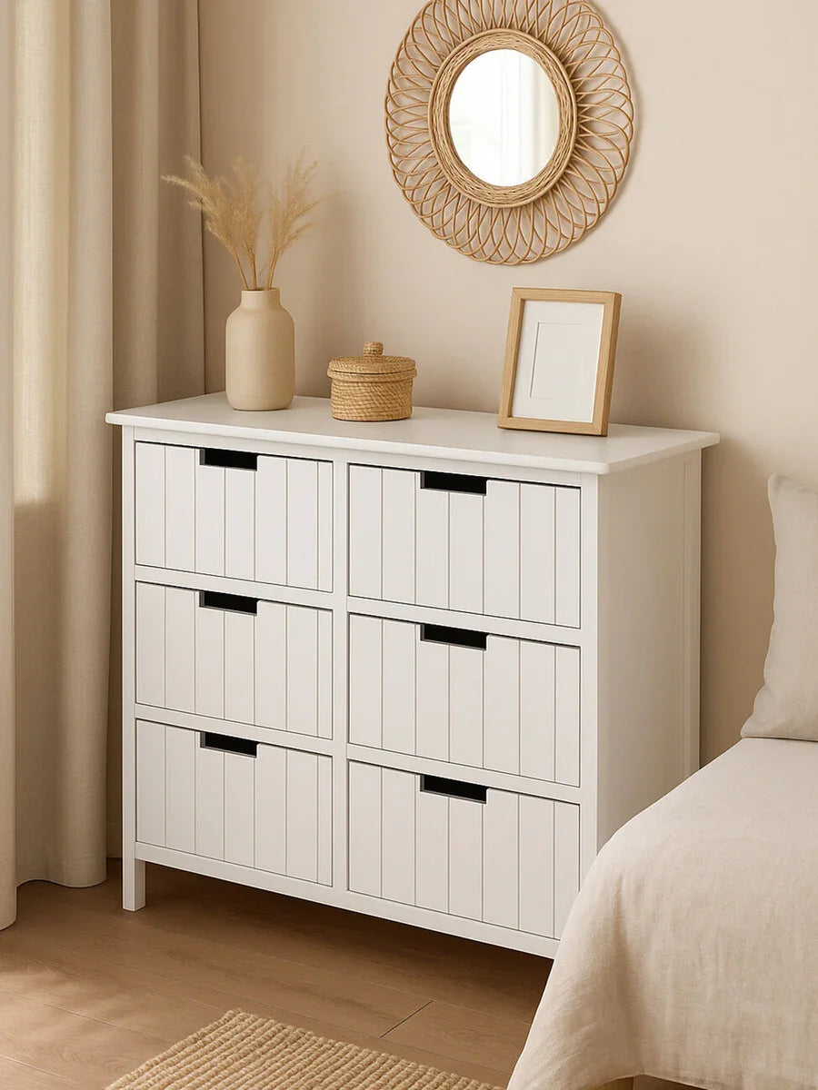 White wooden chest of drawers with six drawers in a neutral bedroom setting