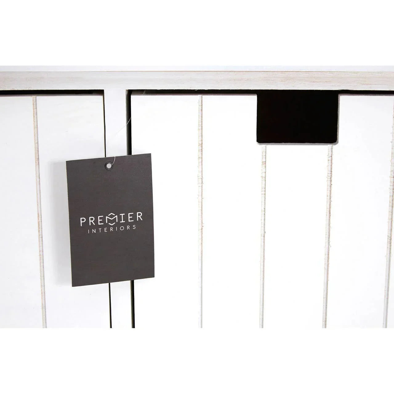 Closeup of white wooden furniture panel with vertical grooves and black Premier Interiors tag