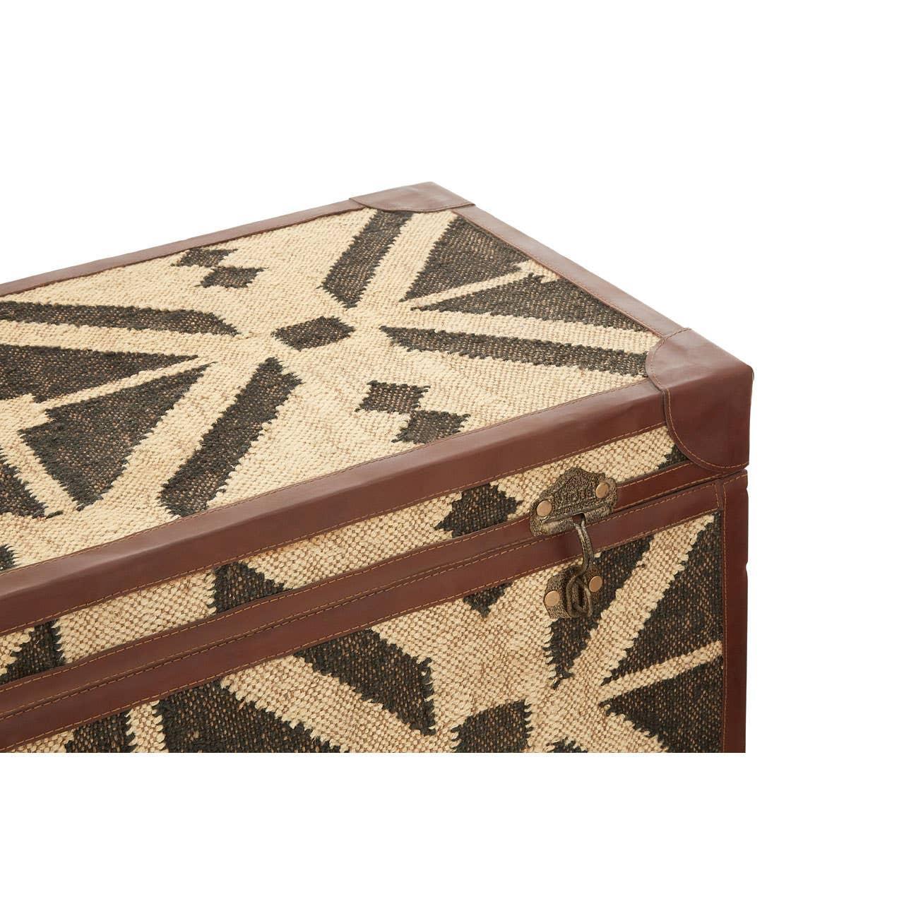 Patterned storage trunk with brown leather trim and brass latch, close top corner view