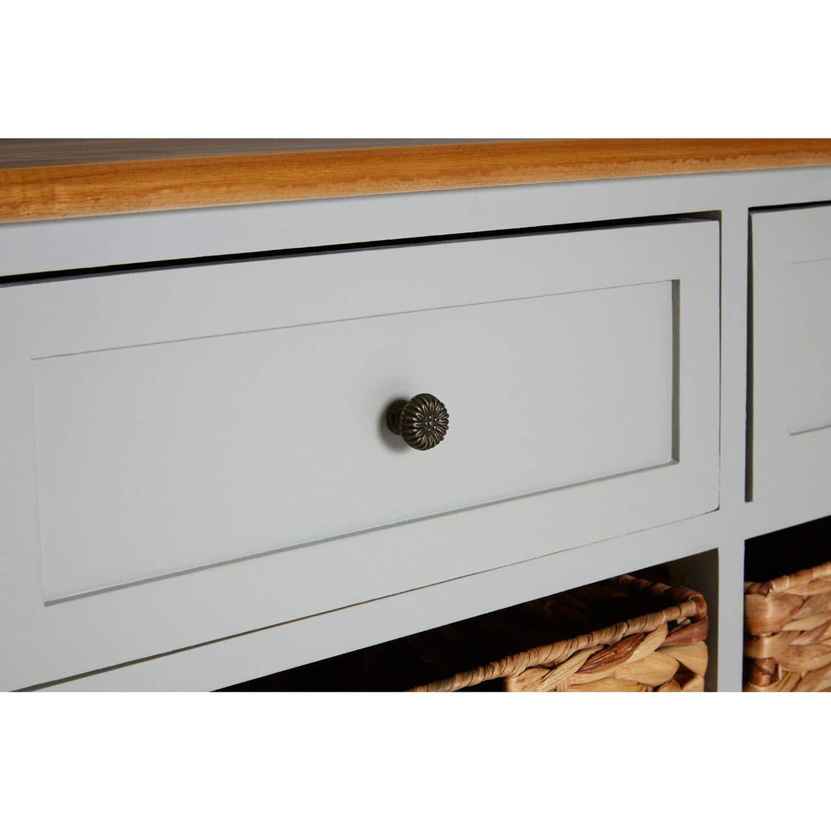 The Vermont Two Drawers Four Baskets Cabinet features a light gray finish with a smooth wooden top. It includes two spacious drawers with round bronze knobs and four woven baskets below, providing stylish storage options. The cabinet has clean lines and a modern design, suitable for various home decor styles