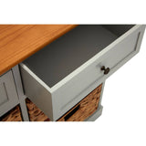 A close-up view of the Vermont Two Drawers Four Baskets Cabinet, showcasing an open drawer with a smooth gray interior and a wooden top. The cabinet features a light gray finish with woven baskets below the drawers, highlighting its functional design and storage capabilities