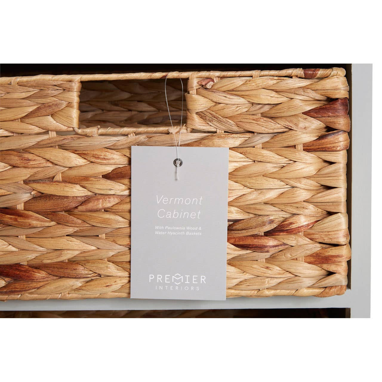 Vermont Two Drawers Four Baskets Cabinet featuring a natural woven texture, two wooden drawers with metal handles, and four wicker baskets arranged below, all set against a light-colored wooden frame. A small tag is attached to one of the drawers