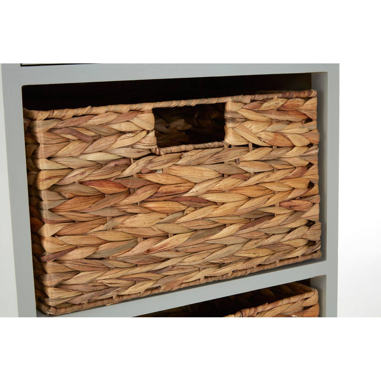 A close-up view of the Vermont One Drawer Two Baskets Cabinet, showcasing a wooden drawer with a metal handle and two woven baskets below, all set against a light gray frame. The texture of the wood and the natural fibers of the baskets are clearly visible