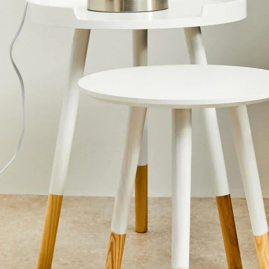 Set of two white round side tables with natural wood legs, lamp on larger table