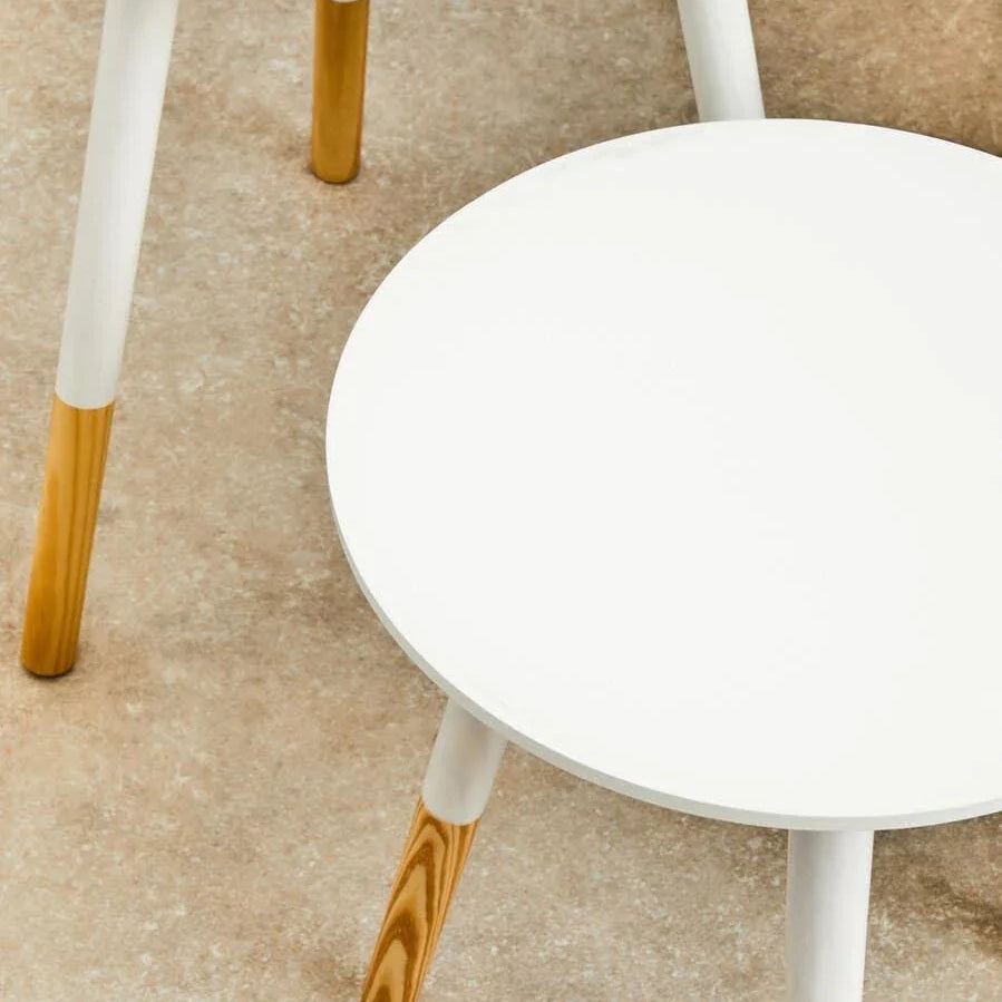 Round white side tables with wooden legs on beige floor