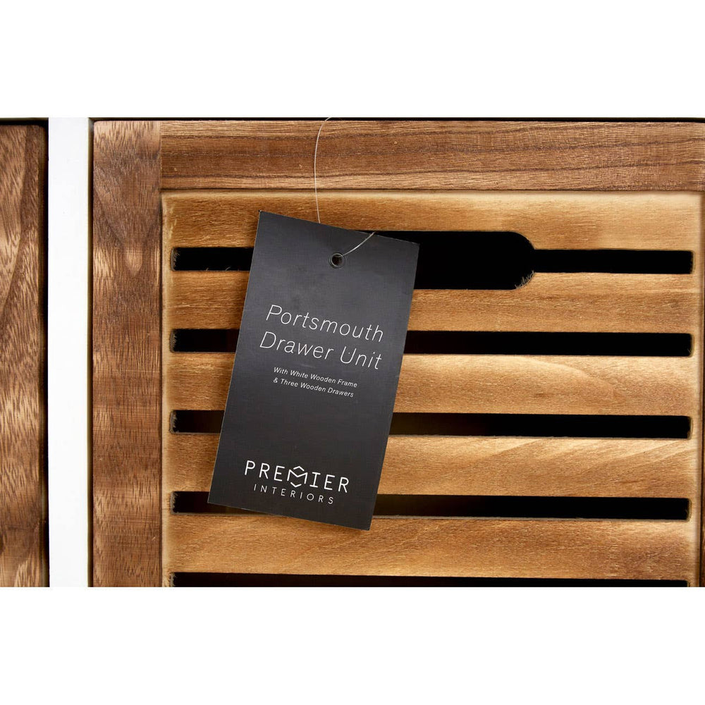 Natural wood drawer chest featuring slatted design on the front, with a black tag attached that displays the product name and details. The wood has a warm, rich finish, highlighting its natural grain