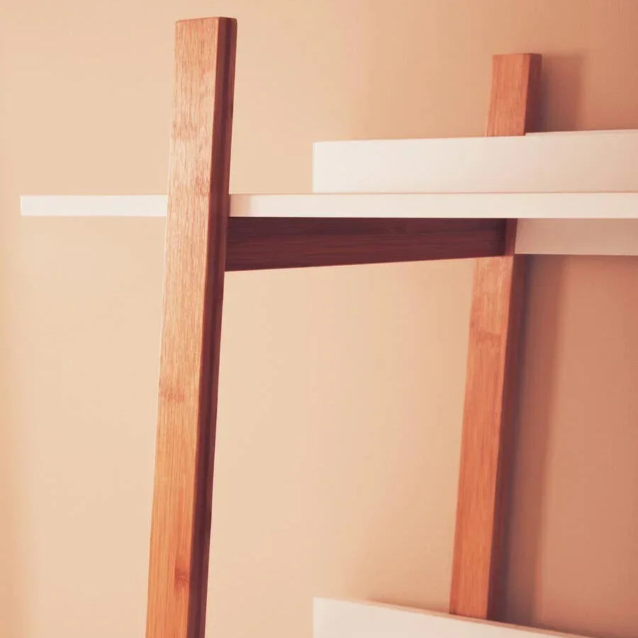 Modern shelving unit with white shelves and angled oak wood supports against beige wall