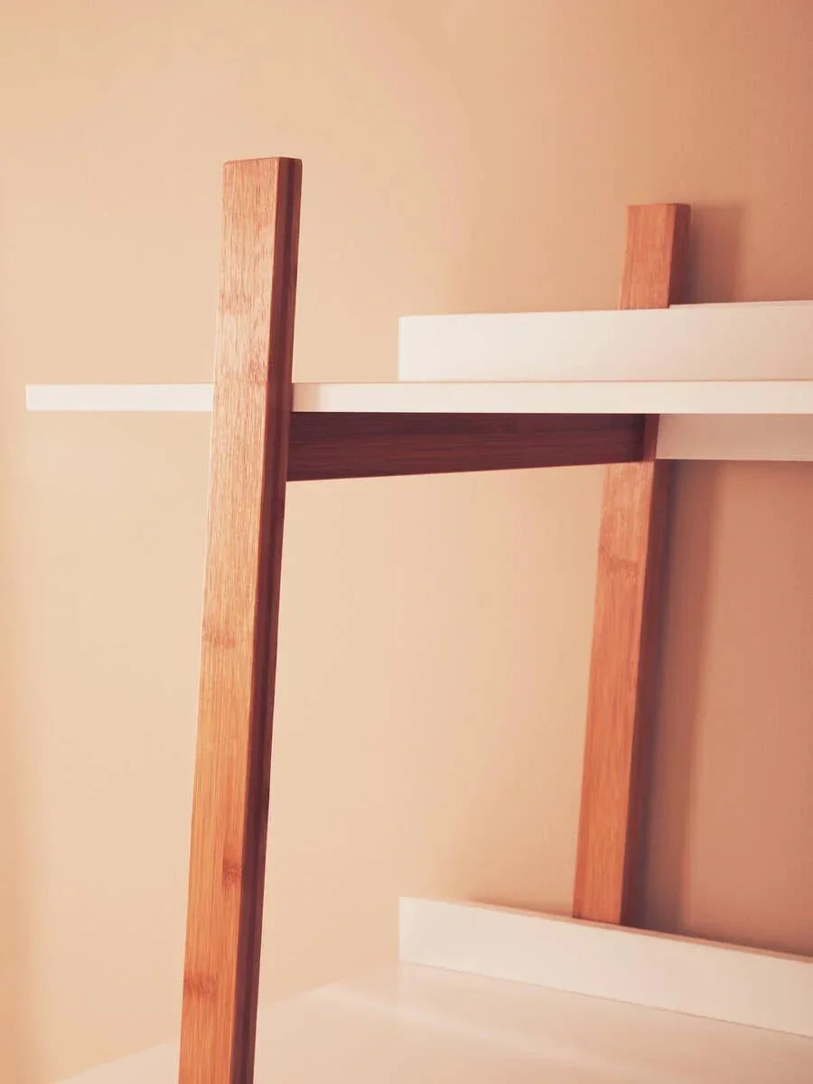 Modern shelving unit with white shelves and angled oak wood supports against beige wall