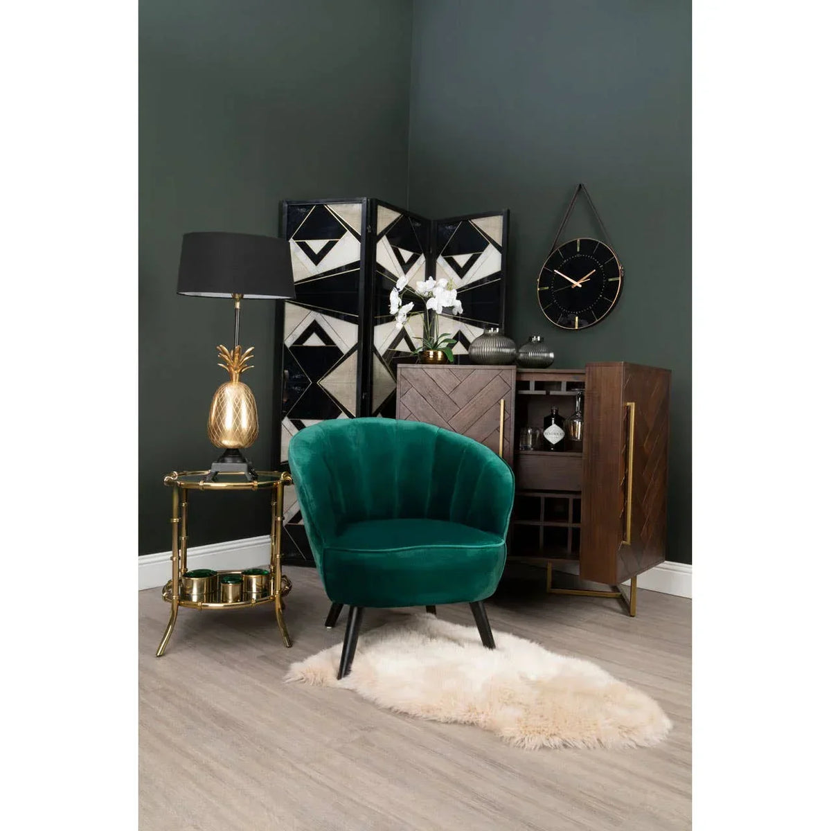 Green velvet accent chair with black legs in modern living room setup with gold side table