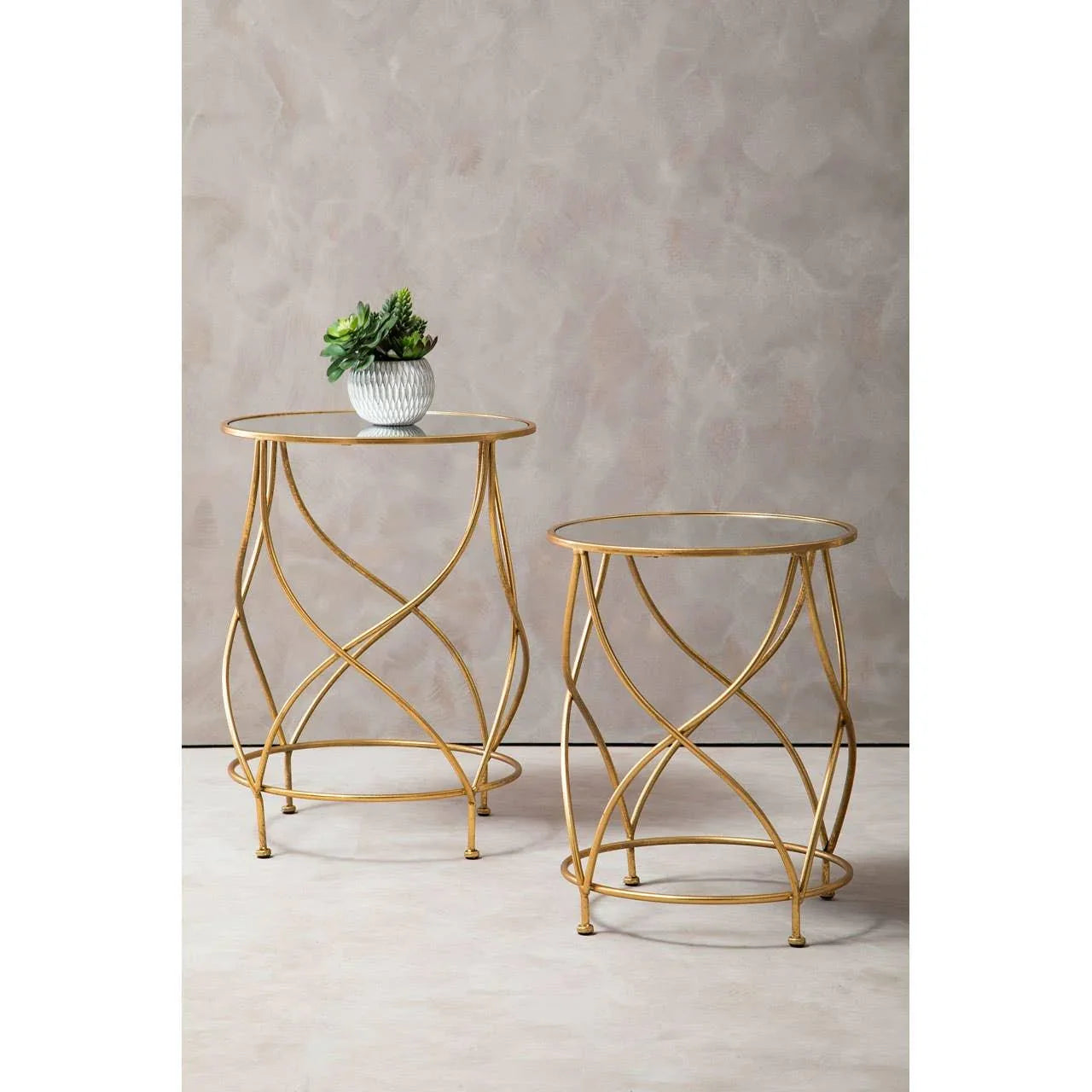 Gold metal and glass side tables with decorative base, one with a small potted plant