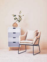 Milo Chest of 4 Drawers in a modern design featuring a white and light blue color scheme, positioned next to a light beige armchair with a minimalist frame. A decorative vase with greenery sits atop the chest, against a soft pastel background