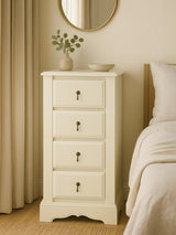 Florence Ivory Chest of 4 Drawers featuring a smooth, light ivory finish, four spacious drawers with decorative handles, and a curved base, positioned next to a bed with a neutral-colored duvet and a round mirror above it, complemented by a small vase of flowers on top